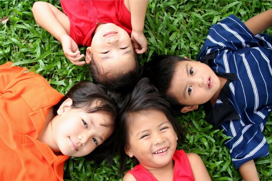Aerial view of a family of 4 kids smiling in the grass in Kerrville, TX after a trip to the dentist