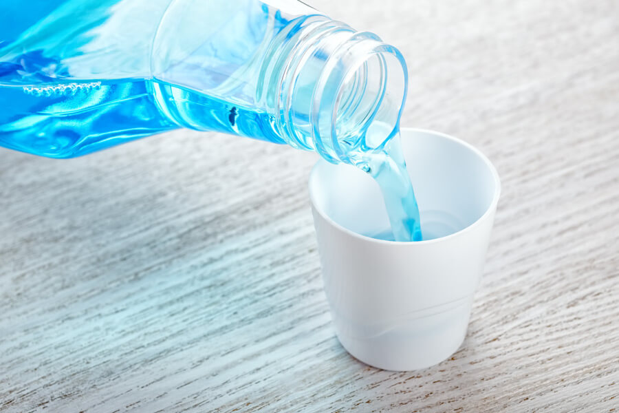 Blue mouthwash being poured into a white cup