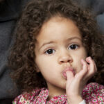 Curly-haired young girl has a thumb sucking habit